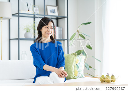 A middle-aged woman relaxing in the living room 127990287