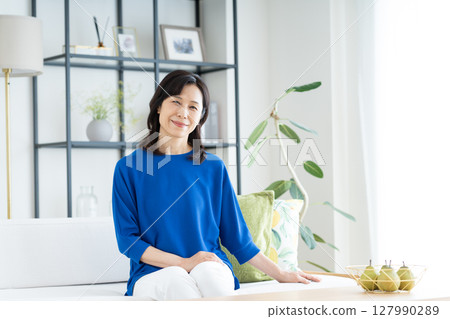 A middle-aged woman relaxing in the living room A middle-aged woman relaxing in the living room 127990289