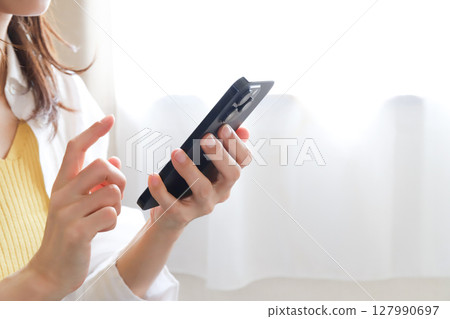 Woman operating a smartphone Woman operating a smartphone 127990697