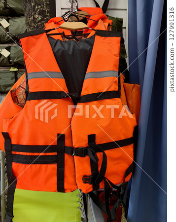bright orange life vest displayed in a retail store for safety gear purchase. closeup. 127991316