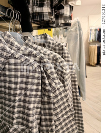 plaid shirts hanging in retail store display and clothing racks for fall season shopping. closeup. plaid shirts hanging in retail store display and clothing racks for fall season shopping. closeup. 127991318