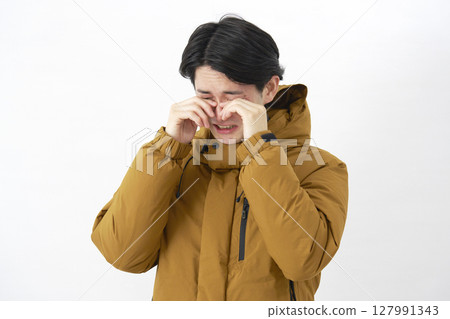 A man wearing a down jacket crying on a white background A man wearing a down jacket crying on a white background 127991343