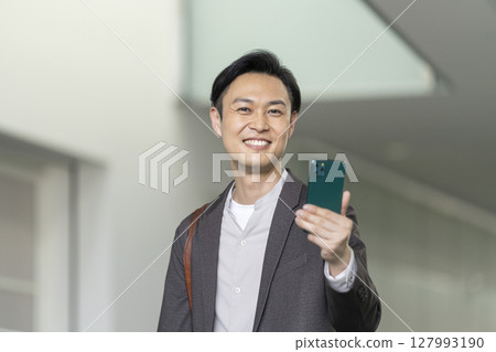 A smiling man in his 40s holding a smartphone A smiling man in his 40s holding a smartphone 127993190