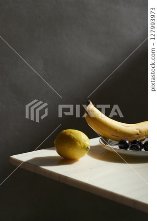 A cozy backdrop with fresh fruits and grass on a table with natural sunlight and shadows. 127993973