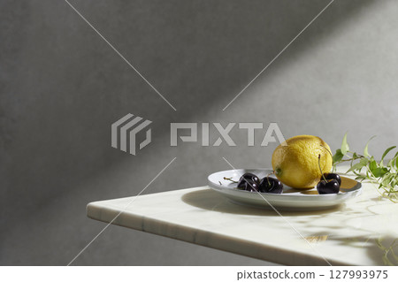 A cozy backdrop with fresh fruits and grass on a table with natural sunlight and shadows. 127993975