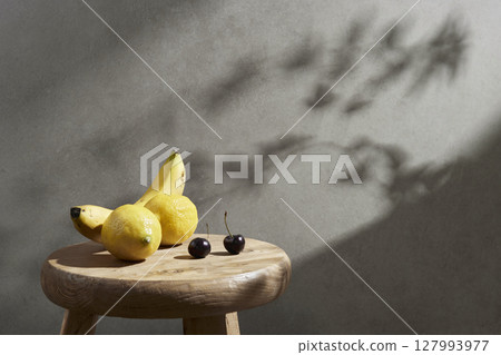 A cozy backdrop with fresh fruits and grass on a table with natural sunlight and shadows. 127993977