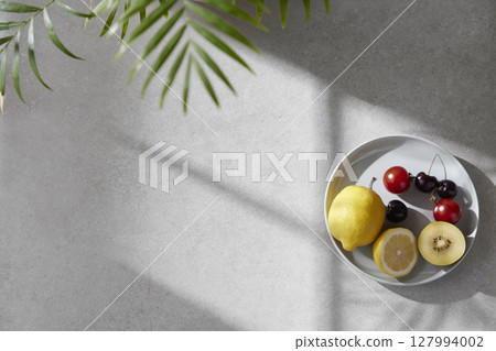 A cozy backdrop with fresh fruits and grass on a table with natural sunlight and shadows. A cozy backdrop with fresh fruits and grass on a table with natural sunlight and shadows. 127994002