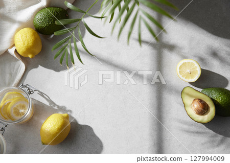 A cozy backdrop with fresh fruits and grass on a table with natural sunlight and shadows. 127994009