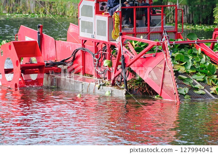 A boat harvesting aquatic plants is harvesting them. A boat harvesting aquatic plants is harvesting them. 127994041