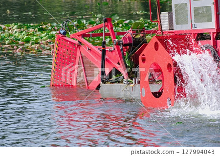 A boat harvesting aquatic plants is harvesting them. 127994043