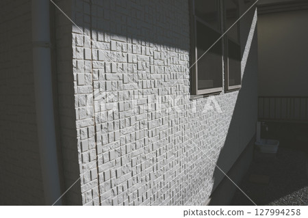 Shadows falling on the exterior wall of a detached house 127994258