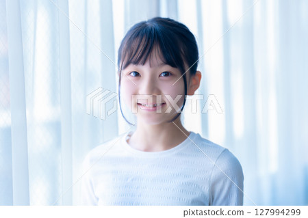 Female junior high school student relaxing by the window Female junior high school student relaxing by the window 127994299