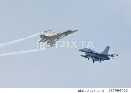 Two fighter planes on a background of white clouds in a blue sky 127994462