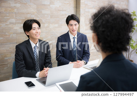 Images of multiple young salesmen explaining to customers at their desks, meetings, etc. 127994497