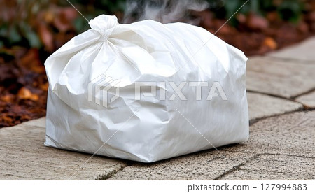 Full white plastic trash bag on paved surface 127994883