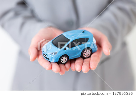 一位身穿灰色西裝的中年婦女，手裡拿著一輛模型車 127995556