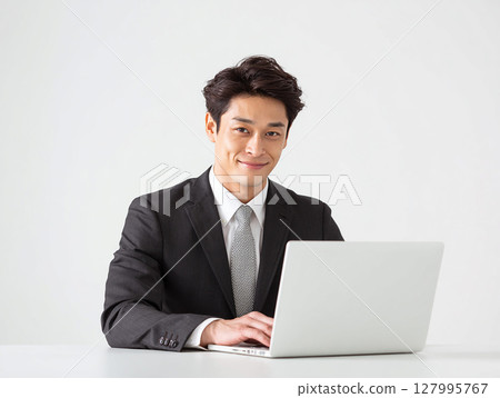 Portrait of a smiling young businessman in a suit working on a computer 127995767