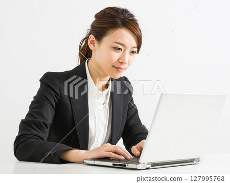 Portrait of a young female business person in a suit concentrating on computer work 127995768