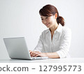 Portrait of a young female business person working on a computer against a white background 127995773