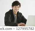 Positive business portrait of a smiling young man working on a computer 127995782