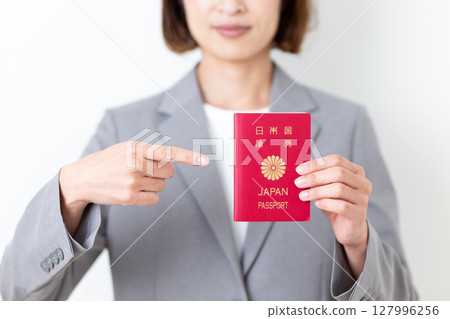 A middle-aged woman in a gray suit pointing at her passport A middle-aged woman in a gray suit pointing at her passport 127996256