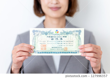 一位身穿灰色西裝、手持股票的中年婦女 127996357