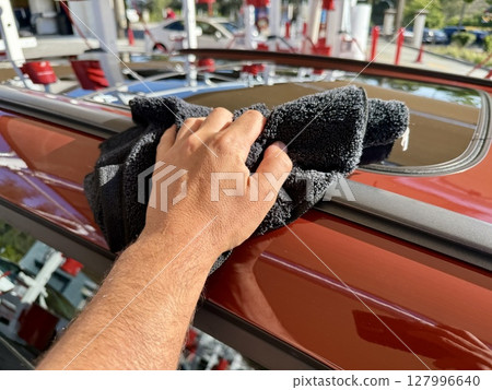 Man hand cleaning car with microfiber cloth at car wash Man hand cleaning car with microfiber cloth at car wash 127996640