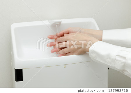 Woman washing her hands in the bathroom 127998716