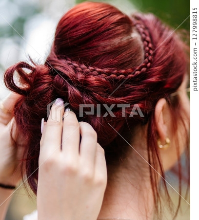 Hair stylist works on the head of a woman 127998815