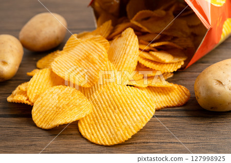 Potato chips, delicious BBQ seasoning spicy for crips, thin slice deep fried snack fast food in open bag. 127998925