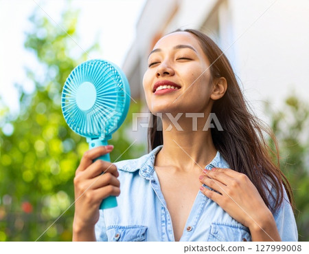 A woman holding a handheld fan 127999008