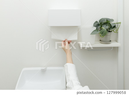 Woman's hand using a paper towel in the toilet 127999058