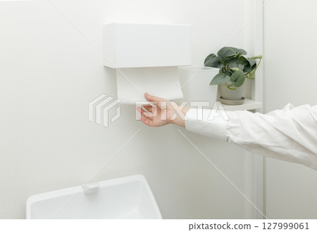 Woman's hand using a paper towel in the toilet Woman's hand using a paper towel in the toilet 127999061
