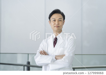 一名 40 多歲的男子身穿白大褂，雙臂交叉，看著鏡頭，醫生/研究人員圖像 127999068