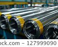Stack of polished metal pipes inside a modern industrial warehouse, focus on steel texture. 127999090