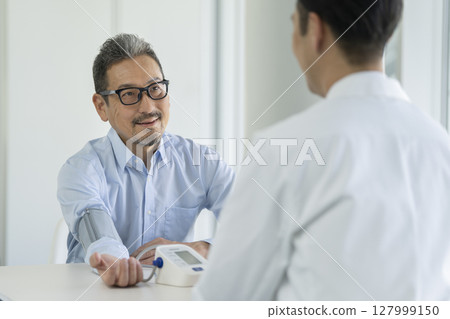 Senior man having blood pressure measurement 127999150