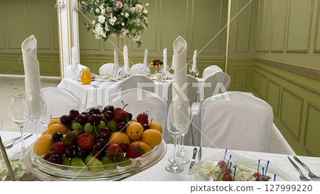 Beautiful banquet table adorned with fresh fruits, including grapes, strawberries, and peaches. The elegant setting is perfect for a special event, wedding reception, or family celebration 127999220