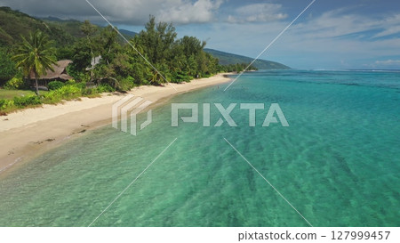 Stunning aerial view of a tropical beach with crystal-clear turquoise water gently lapping against the shore, inviting tourists to swim and relax amidst lush green vegetation and palm trees Stunning aerial view of a tropical beach with crystal-clear turquoise water gently lapping against the shore, inviting tourists to swim and relax amidst lush green vegetation and palm trees 127999457