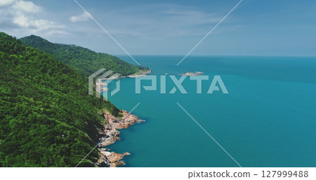 Aerial drone footage revealing the stunning beauty of a tropical island, with lush green mountains meeting turquoise ocean waters under a cloudy sky Aerial drone footage revealing the stunning beauty of a tropical island, with lush green mountains meeting turquoise ocean waters under a cloudy sky 127999488