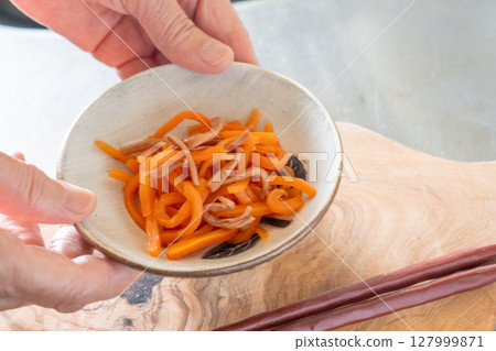 Person serving squid and carrots 127999871