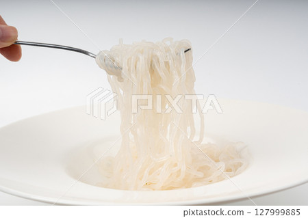 Shirataki or konnyaku pasta in white plate on fork close up. Konjak jelly noodles Shirataki or konnyaku pasta in white plate on fork close up. Konjak jelly noodles 127999885