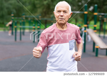 Active senior man is jogging in summer park. Healthy retirement lifestyle Active senior man is jogging in summer park. Healthy retirement lifestyle 127999889