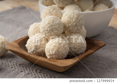 Coconut candies pile, coco ball. White truffle ball, indian ladoo or laddu with sweet cream and coco Coconut candies pile, coco ball. White truffle ball, indian ladoo or laddu with sweet cream and coco 127999914