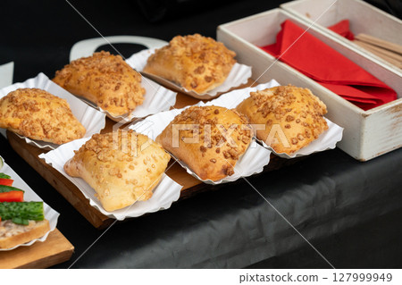 Baked pastries with sweet crumble topping are served on white paper trays 127999949