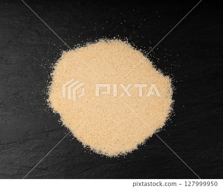 Garlic powder pile, dried granulated chopped crushed garlic cloves, cut into small pieces 127999950