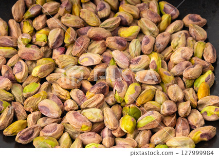 Fried salt pistachio nuts texture background. Baked pistachios grains pattern, pistache fruits 127999984