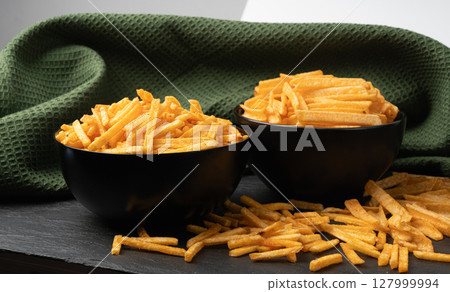 Fried chips sticks, finger potato chips, golden shoestring fries pile, French fries 127999994