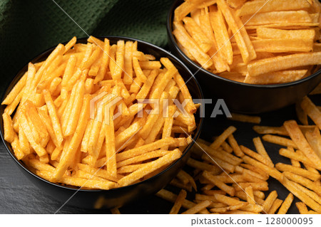 Fried chips sticks, finger potato chips, golden shoestring fries pile, French fries 128000095