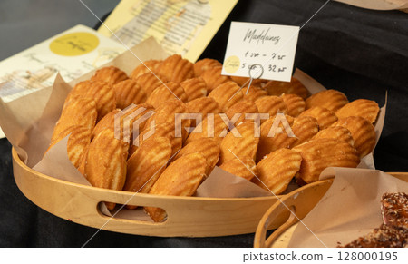 Madeleines or french tea cakes in a basket, spongy texture cookies, golden soft biscuits, tea snacks 128000195