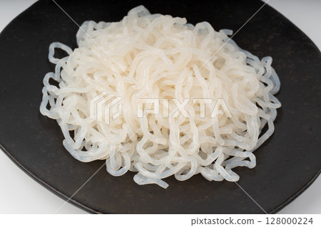Shirataki or konnyaku pasta on black plate close up. Konjak jelly noodles Shirataki or konnyaku pasta on black plate close up. Konjak jelly noodles 128000224